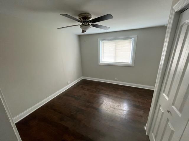 spare room featuring a ceiling fan, baseboards, and dark wood-style flooring