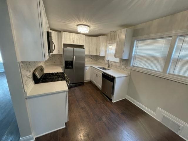 kitchen featuring visible vents, dark wood-style flooring, stainless steel appliances, light countertops, and a sink