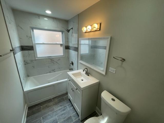 full bath featuring toilet,  shower combination, wood finish floors, and vanity