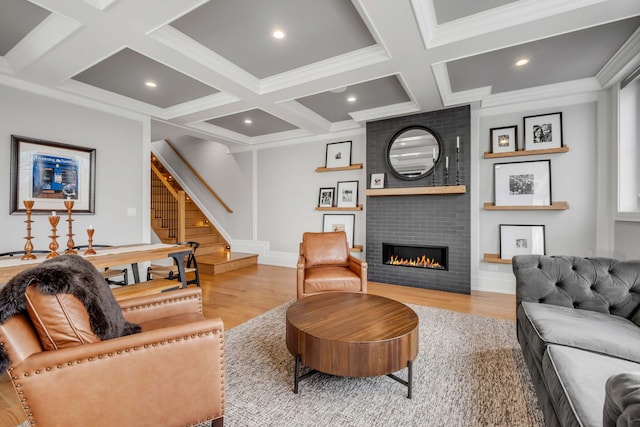 living room with light wood-style flooring, a fireplace, beam ceiling, and stairs