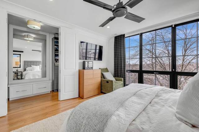 bedroom with expansive windows, ceiling fan, multiple windows, and wood finished floors