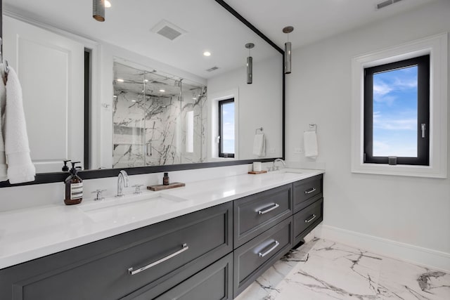 bathroom with marble finish floor, a marble finish shower, double vanity, a sink, and baseboards