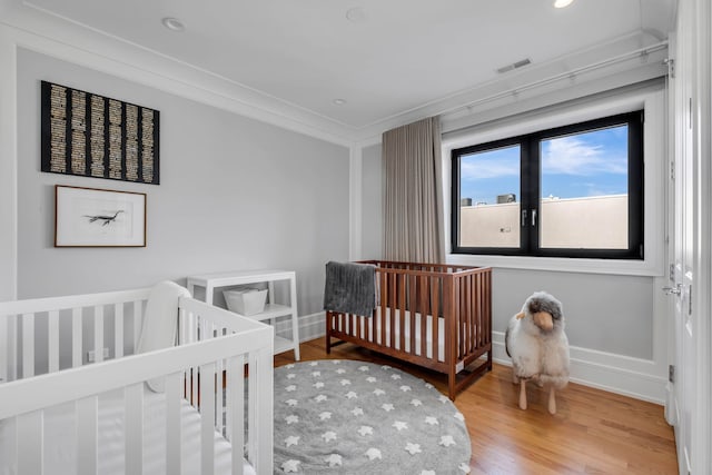 bedroom with baseboards, visible vents, wood finished floors, crown molding, and recessed lighting