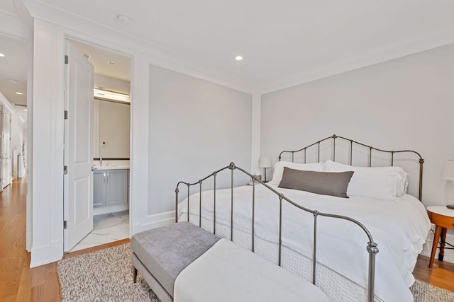 bedroom featuring light wood-type flooring, recessed lighting, baseboards, and ensuite bathroom