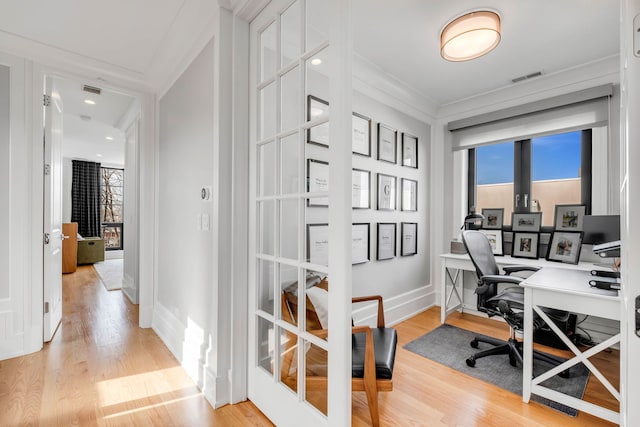 office featuring ornamental molding, light wood finished floors, visible vents, and a healthy amount of sunlight