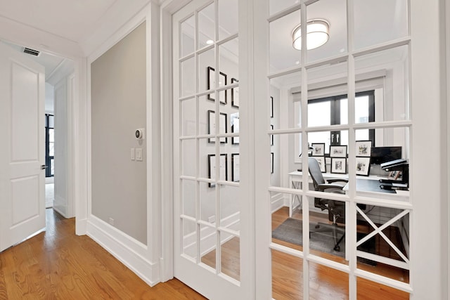 corridor with french doors, wood finished floors, visible vents, and baseboards