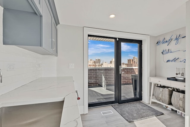 doorway to outside with light wood-style floors, a view of city, visible vents, and expansive windows