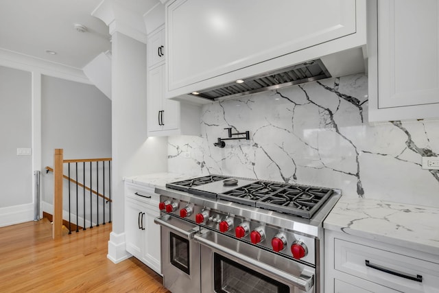 kitchen featuring light stone counters, double oven range, and white cabinetry