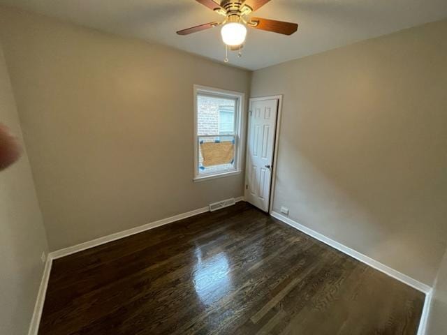 unfurnished room with dark wood-style floors, ceiling fan, visible vents, and baseboards