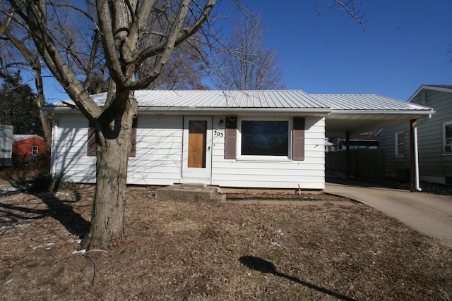 ranch-style home featuring an attached carport, metal roof, and concrete driveway