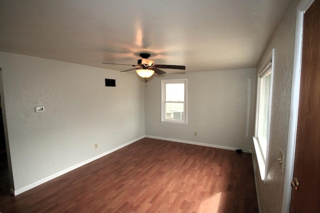 spare room featuring dark wood-style floors, baseboards, visible vents, and a ceiling fan