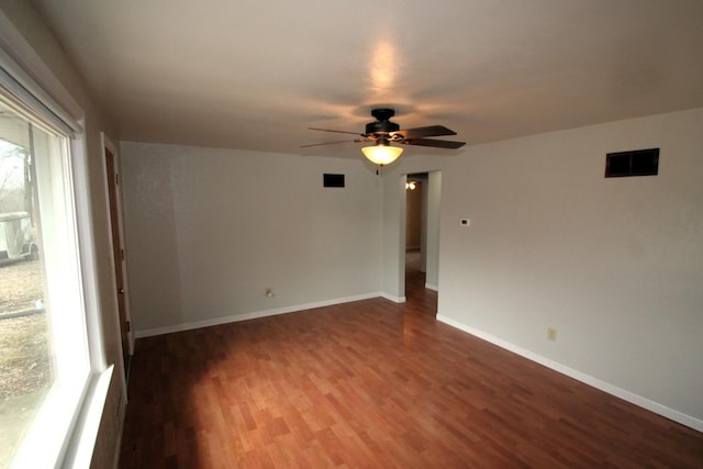 spare room with dark wood-style floors, visible vents, baseboards, and a ceiling fan