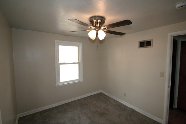 spare room featuring baseboards, visible vents, dark colored carpet, and a ceiling fan