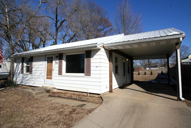 ranch-style house with driveway, metal roof, and an attached carport