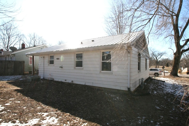 snow covered house featuring metal roof and fence