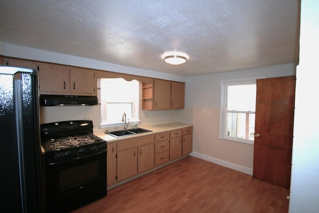 kitchen featuring under cabinet range hood, open shelves, a sink, light countertops, and black appliances