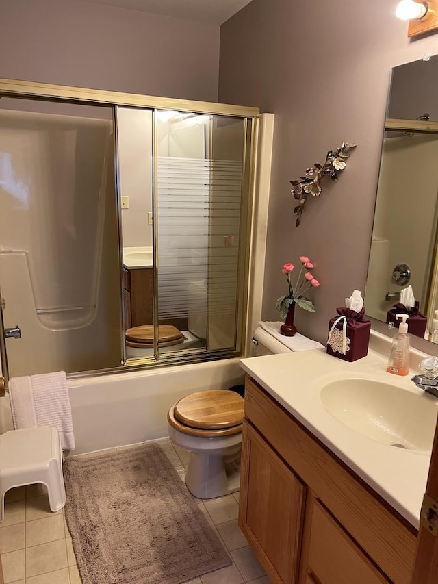 full bath with vanity, tile patterned floors, toilet, and shower / bath combination with glass door