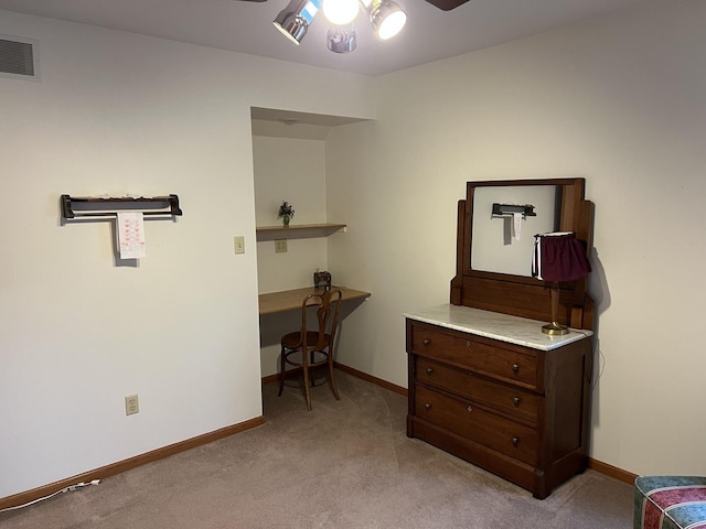 interior space featuring light carpet, visible vents, baseboards, and built in desk