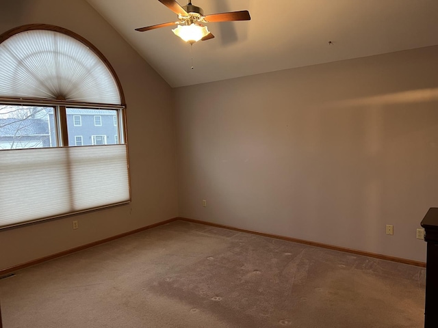 unfurnished room featuring baseboards, lofted ceiling, light colored carpet, and a ceiling fan