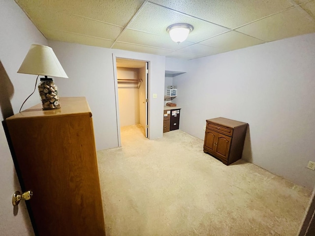 bedroom with a drop ceiling and light colored carpet