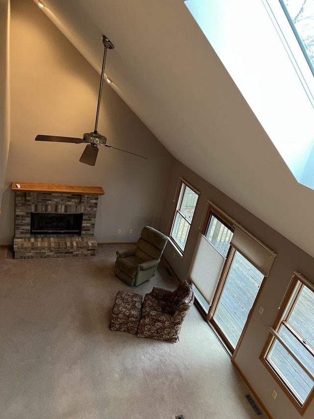 living room with a ceiling fan, visible vents, carpet floors, high vaulted ceiling, and a fireplace