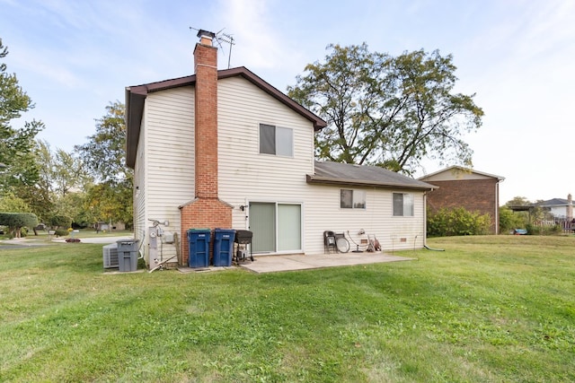 rear view of house featuring a patio, a lawn, a chimney, and cooling unit