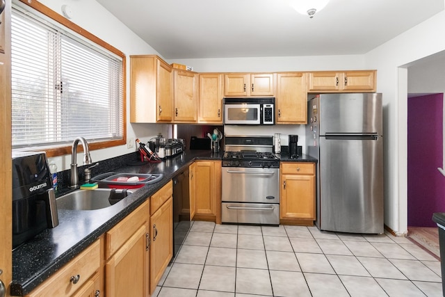 kitchen featuring light tile patterned floors, appliances with stainless steel finishes, dark countertops, and a sink