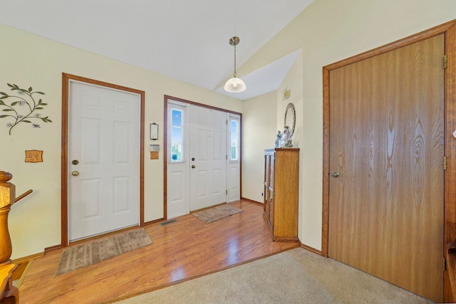 entrance foyer featuring lofted ceiling, light wood finished floors, and baseboards