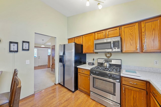 kitchen with stainless steel appliances, light countertops, light wood-style flooring, and brown cabinets