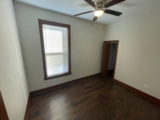 unfurnished room with ceiling fan, dark wood-type flooring, and baseboards