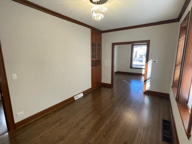 spare room featuring ornamental molding, visible vents, and dark wood-type flooring