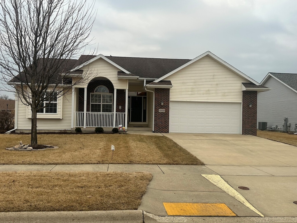 ranch-style home featuring a garage, driveway, central AC, and brick siding