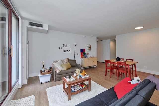 living room featuring light wood-style floors, baseboards, and visible vents