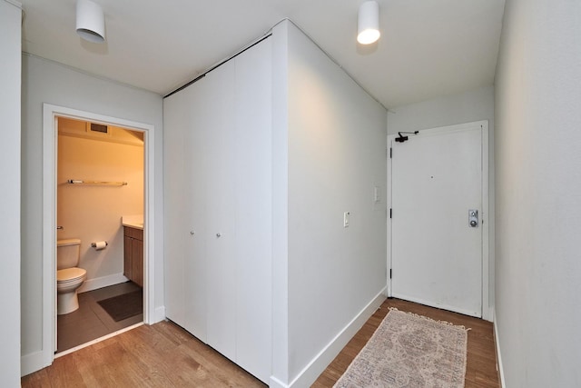 hall with baseboards, visible vents, and wood finished floors