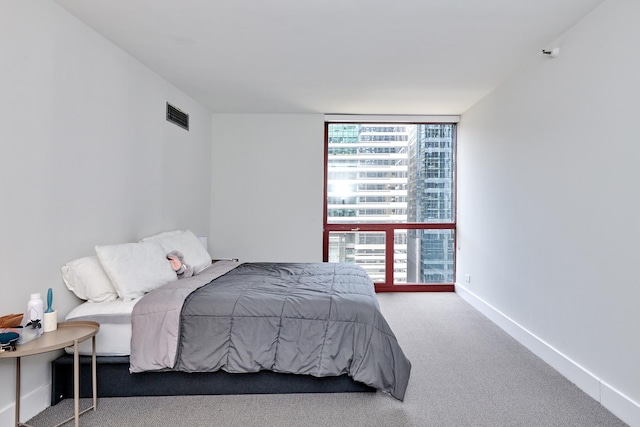 carpeted bedroom with baseboards, floor to ceiling windows, visible vents, and multiple windows