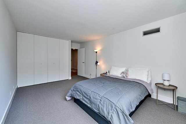 bedroom with dark colored carpet, a closet, visible vents, and baseboards