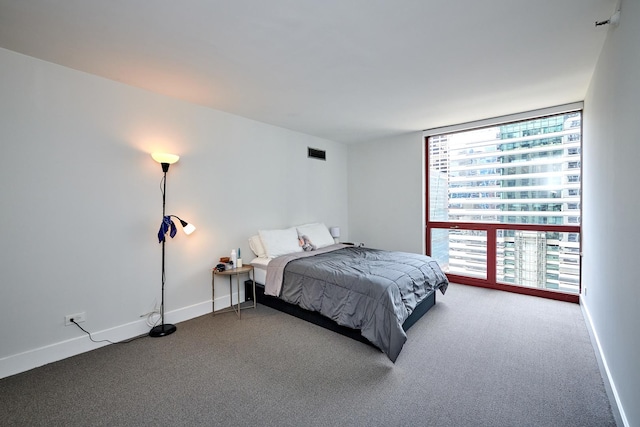 carpeted bedroom featuring a wall of windows, visible vents, and baseboards