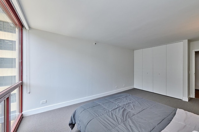 bedroom featuring baseboards, dark carpet, and a closet