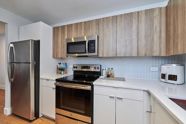 kitchen with stainless steel appliances, light countertops, decorative backsplash, and modern cabinets