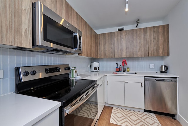 kitchen with white cabinets, brown cabinetry, appliances with stainless steel finishes, and light countertops