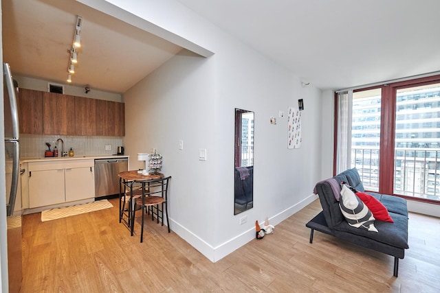 kitchen featuring decorative backsplash, open floor plan, stainless steel appliances, light countertops, and a sink