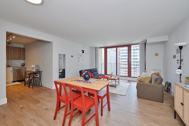 dining room featuring expansive windows, light wood finished floors, and baseboards