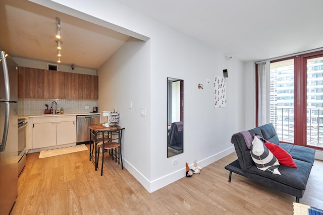 kitchen featuring tasteful backsplash, baseboards, appliances with stainless steel finishes, light countertops, and light wood-style floors