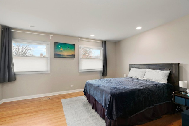 bedroom with light wood-style floors, multiple windows, visible vents, and baseboards