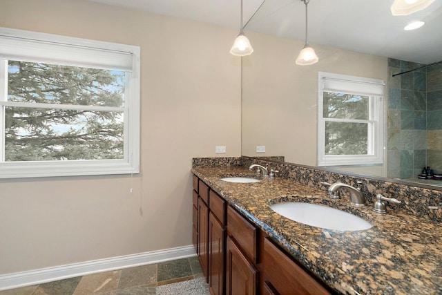 full bath with double vanity, baseboards, and a sink