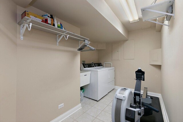 washroom featuring laundry area, washer and clothes dryer, light tile patterned flooring, and baseboards