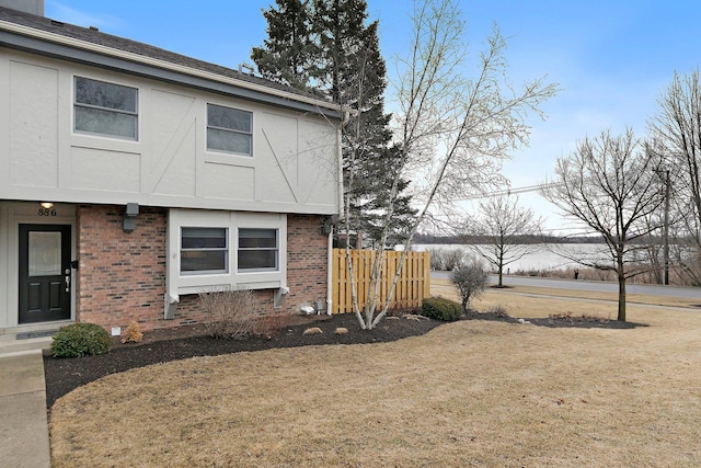 view of side of home featuring stucco siding, fence, and brick siding