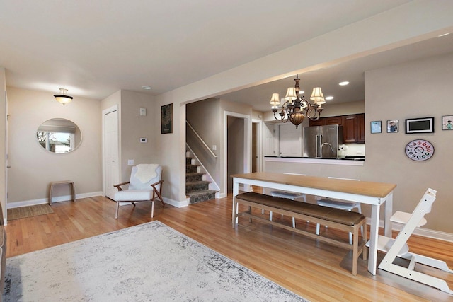 dining area with stairs, baseboards, a notable chandelier, and light wood-style floors