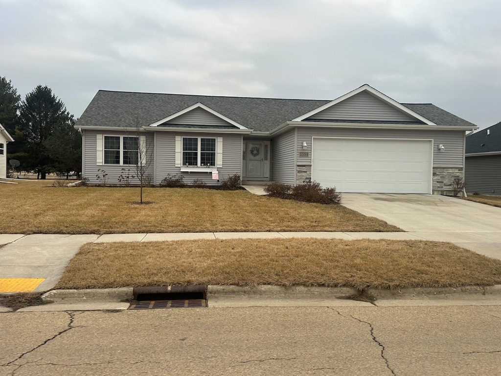 single story home with a garage, driveway, a front lawn, and roof with shingles