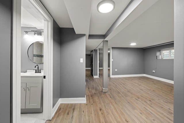 interior space featuring light wood finished floors, baseboards, and a sink